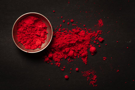 Close-up of auspicious red orange colored Sindoor or kumkum in brass small bowl during any Hindu pooja over blackの写真素材