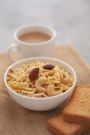 Close-Up of crunchy Indian mixture snacks with hot tea or Coffee time and handmade cookies (biscuits). Studio shoot at declined angle.の写真素材