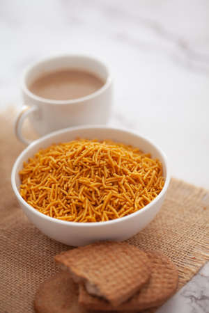 Close-Up of crunchy Indian mixture snacks with hot tea or Coffee time and handmade cookies (biscuits). Studio shoot at declined angle.の写真素材