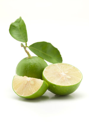 Close-up of fresh green organic lemon (Citrus limon) and sliced lemon  with leaf  isolated over white.の写真素材