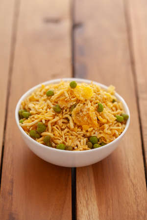 Close-up of cornflakes mixture Indian namkeen (snacks),  Indian salted snacks (Namkeen),in white ceramic bowl over wooden  backgroundの写真素材