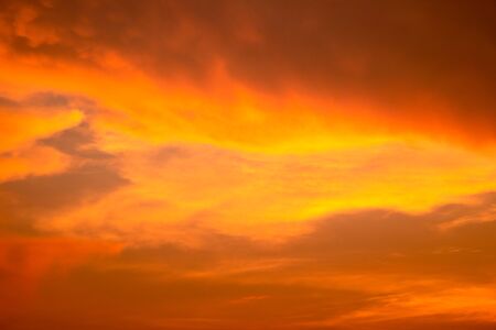Cloudy sky and orange light of the sun through the cloudsの写真素材