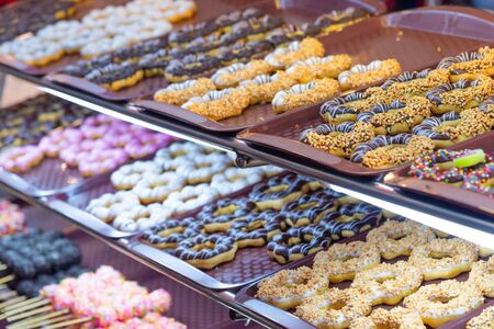 Various colorful fancy donuts or doughnut on tray for sale at street food market.の写真素材