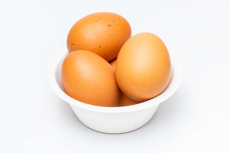 Isolated pile of brown organic egg in a biodegradable paper bowl on white background.の写真素材