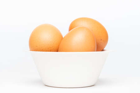 Isolated pile of brown organic egg in a biodegradable paper bowl on white background.の写真素材