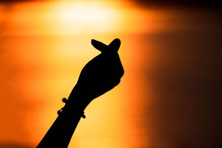 Silhouette hand in mini heart shape with sunset,Love concept. Happy Valentine's Dayの写真素材