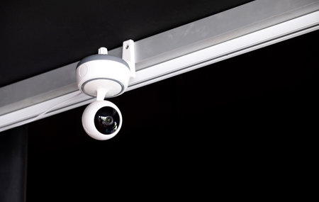 modern white surveillance camera, mounted on the ceiling in the living room, to record the events...
