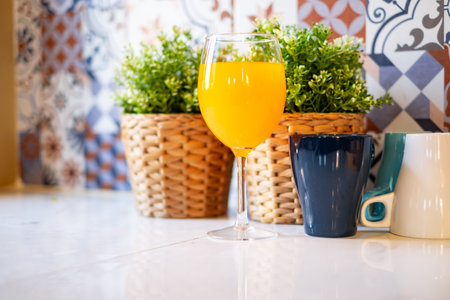 Orange juice in a wine glass is placed on the table in the kitchen.の写真素材