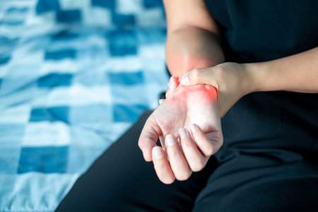 Close up Woman holding wrist due to wrist injury at home, medical treatment, first aid, Healthcare and medical concept.の写真素材