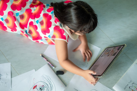 Asian girl, 5-6 years old, practicing origami using video clips or studying online via tablet at home, distance learning, education at home, work form homeの写真素材