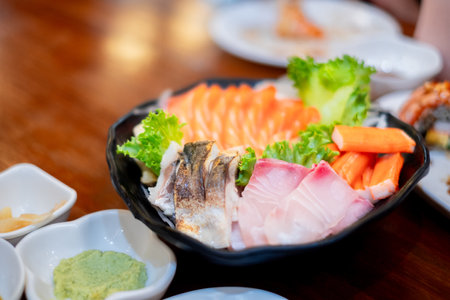 Fresh assorted sashimi platter with salmon, tuna, crab sticks, and wasabi served on a wooden table â perfect for Japanese cuisine and seafood-themed projectsの写真素材