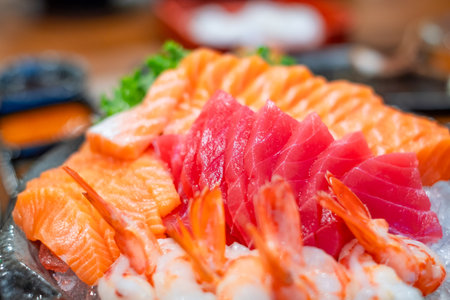 Close up of fresh sashimi with sliced salmon, tuna, and shrimp served on ice, showcasing Japanese cuisine, seafood freshness, gourmet dining, and traditional Asian food presentation.の写真素材