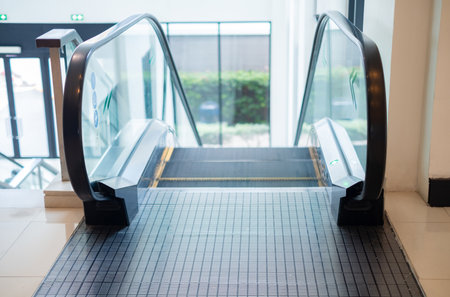 Modern indoor escalator in a commercial building, captured from the top view with clear details of handrails and steps, symbolizing urban lifestyle, convenience, and public transportation concept.の写真素材