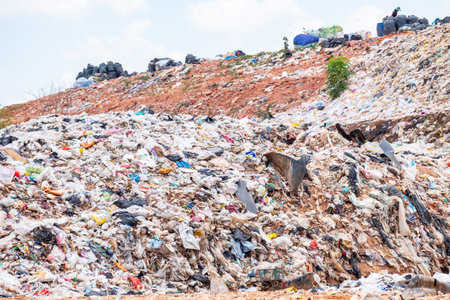 Large pile of plastic waste and garbage in an open landfill under cloudy sky, representing pollution, environment problem, recycling crisis, and global waste management issues for sustainability.の写真素材