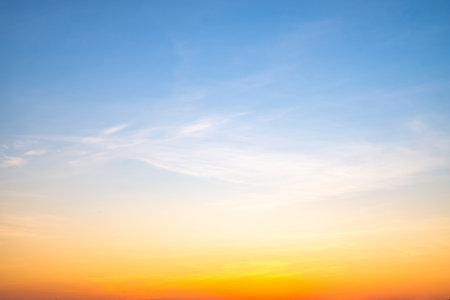 Sunset or sunrise sky with a vibrant gradient of orange, gold, and soft blue. Clear atmosphere with wispy clouds. Peaceful, natural light background. hope, freedom, new day and inspirational Conceptsの写真素材