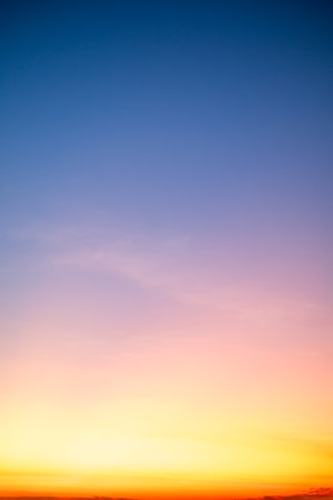 Sunset or sunrise sky with a vibrant gradient of orange, gold, and soft blue. Clear atmosphere with wispy clouds. Peaceful, natural light background. hope, freedom, new day Concepts, Verticalの写真素材