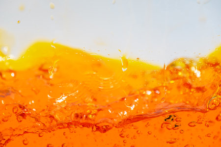 Vibrant orange liquid splashing, creating dynamic waves and droplets. High-speed abstract action...