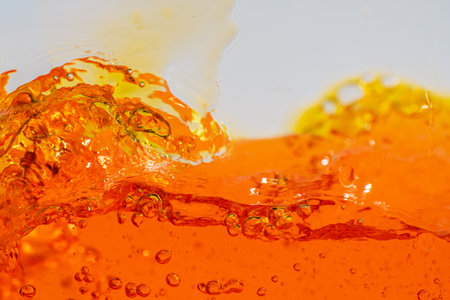 Vibrant orange liquid splashing, creating dynamic waves and droplets. High-speed abstract action shot perfect for beverage, juice, soda, or energy drink advertising and refreshment promotionの写真素材
