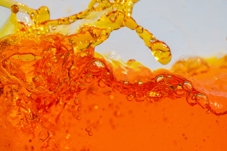 Vibrant orange liquid splashing, creating dynamic waves and droplets. High-speed abstract action shot perfect for beverage, juice, soda, or energy drink advertising and refreshment promotionの写真素材