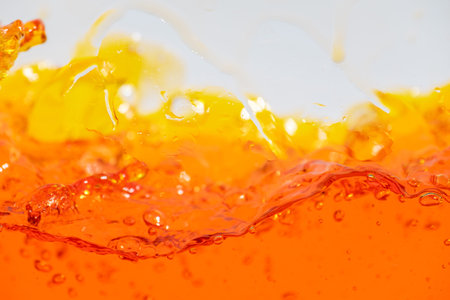 Vibrant orange liquid splashing, creating dynamic waves and droplets. High-speed abstract action shot perfect for beverage, juice, soda, or energy drink advertising and refreshment promotionの写真素材