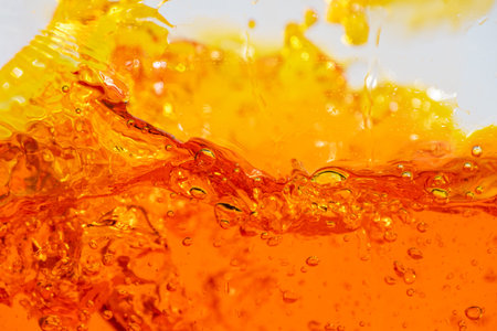 Vibrant orange liquid splashing, creating dynamic waves and droplets. High-speed abstract action...