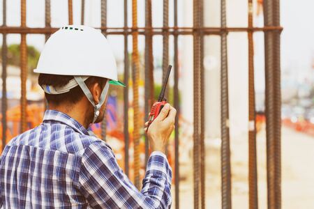 construction supervisor engineers check the project work and use the radio to coordinate with foreman to plan the workの写真素材
