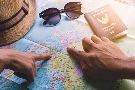 Male and female travelers plan to travel using a world map and a Thailand passport.の写真素材