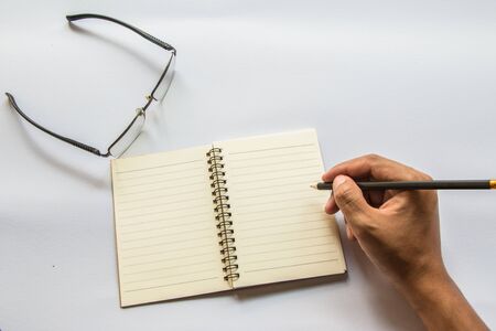 The man is writing a book. There are glasses next to it.の写真素材