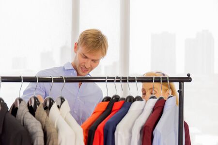 An elderly female designer is explaining information to customers about male suits.の写真素材