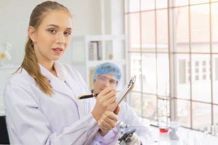 Scientists, young men and women in the laboratory and have a beautiful orange light.