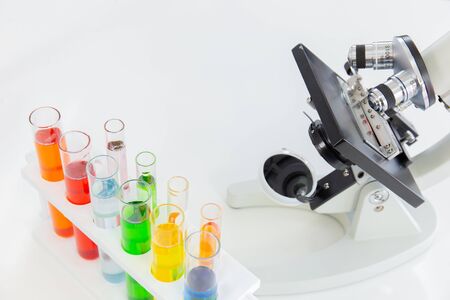 Test tubes in a stand and a microscope on a white tableの写真素材