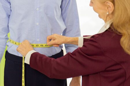 Professional female designers are measuring the size of male customers who use the service for tailoring.の写真素材