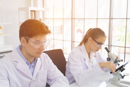 concept of a healthcare researcher, a researcher working in a life science lab, a young research scientist and a male supervisor preparing and analyzing microscopic slides in a research laboratoryの写真素材