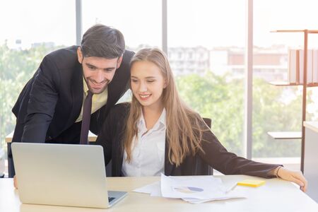 Two young businessmen, men and women, work at the office with a tablet and accompanying documents on the desk with smiles and happiness.の写真素材