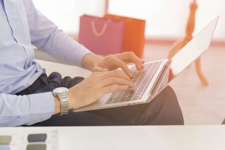 A businessman with a close up in a blue shirt, keyboard, text on a modern notebook computer at a...