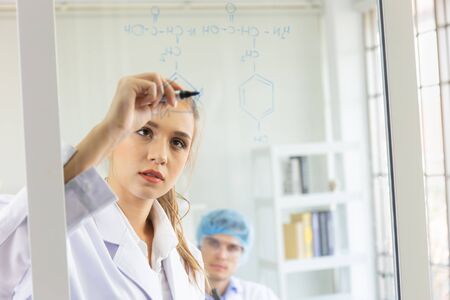 A close-up of a group of young scientists is saving a formula on a glass board.の写真素材