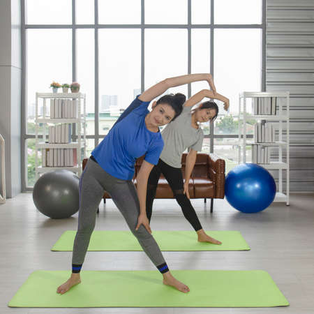 2 Asian female A middle-aged woman is doing yoga on a rubber mat in her home.の写真素材