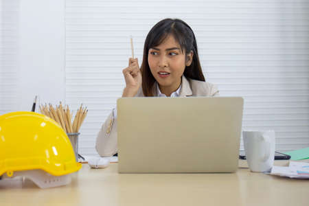 A young Asian professional businesswoman is sleeping on her desk.
