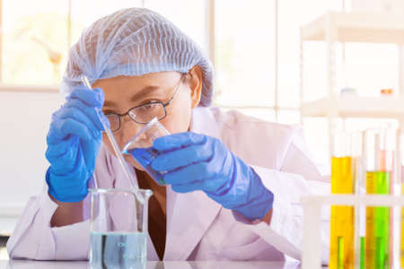 An Asian female scientist is researching a chemical formula in a lab.