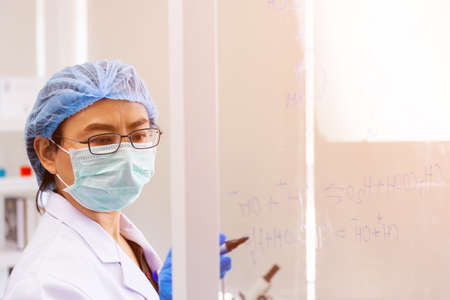 An Asian female scientist is researching a chemical formula in a lab.