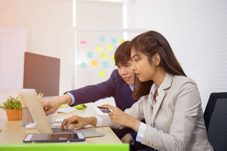 A young professional Asian businesswoman who uses a laptop computer and a credit card to pay online...
