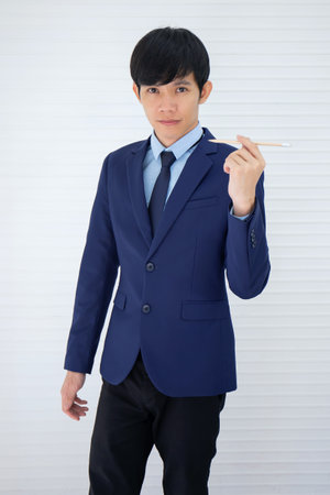 An Asian businessman stood a pencil and his back was a white wall.の写真素材