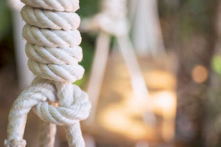 Rope tied in a knot, hanging from a wooden chair.の写真素材