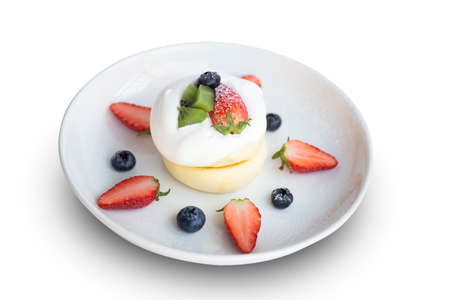 Close-up, Japanese-style pancake topped with mixed fruits, strawberries, kiwi, and blueberries on the top of a cake placed isolated on white background.の写真素材