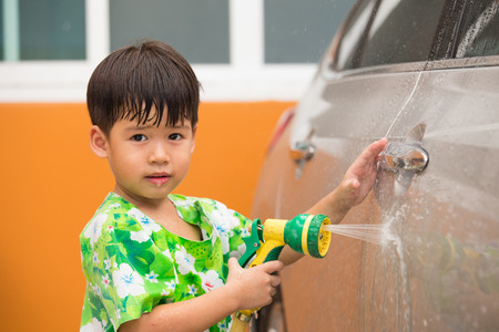 3 years Asian boy is playing water spray for car washの写真素材
