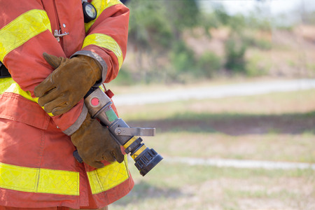 fireman hand in work suit and glove hold fire branch in standby positionの写真素材