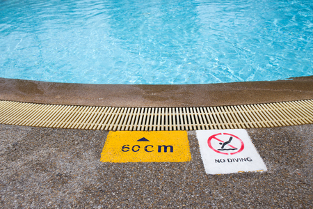 warning and depth sign at clean and clear water swimming pool for children with copy space