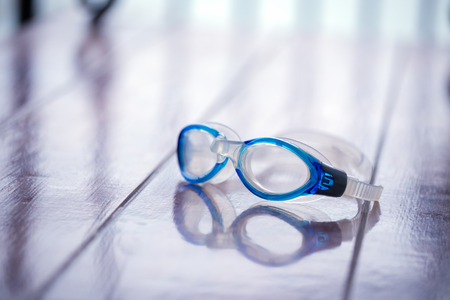 blue swimming goggle isolated on brown wood chair with blue filter and copy spaceの写真素材