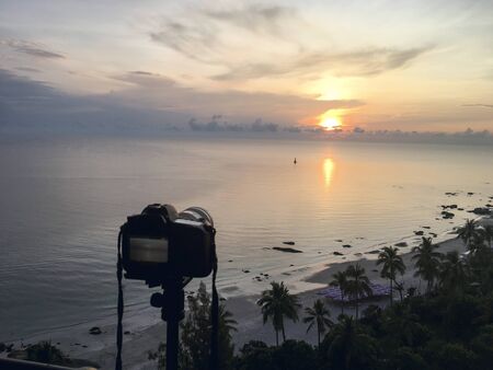 camera on tripod take sunrise picture over sea and beach at Hua Hin, Thailand in warm tone