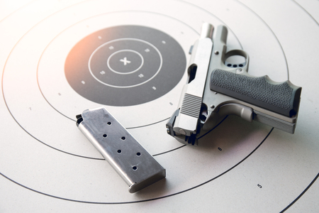 silver .45 pistol with magazine in safety position on bullseye target paper with flare
